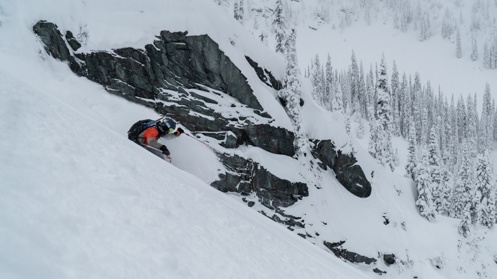 skier slashing a turn down camp west with rocks in the back