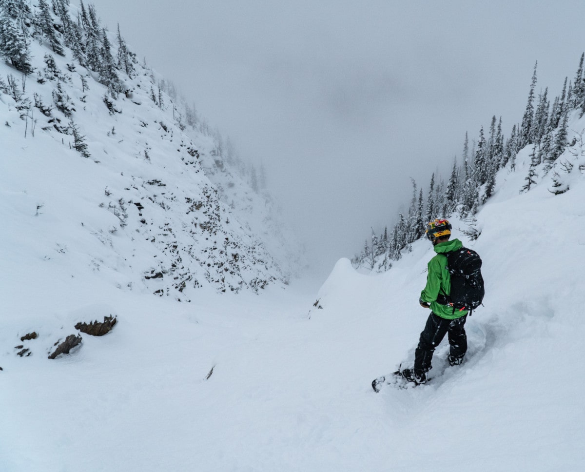 snowboarder scoping out the ross peak couloir with valley bottom clouds