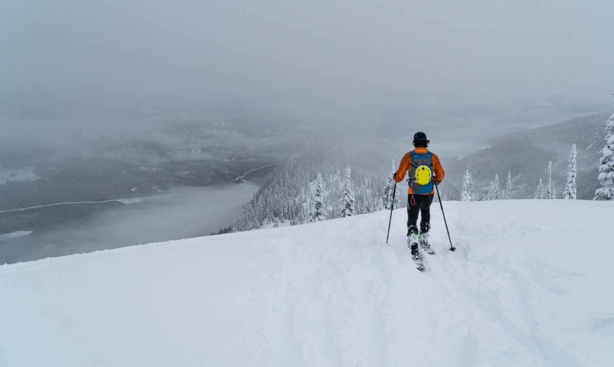 lone ski tourer walking along a ridge in the fog