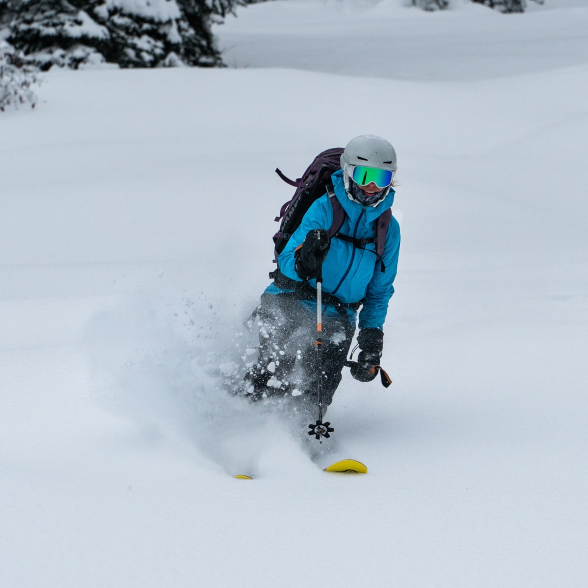 skier in blue jacket skiing through deep powder in christiana trees