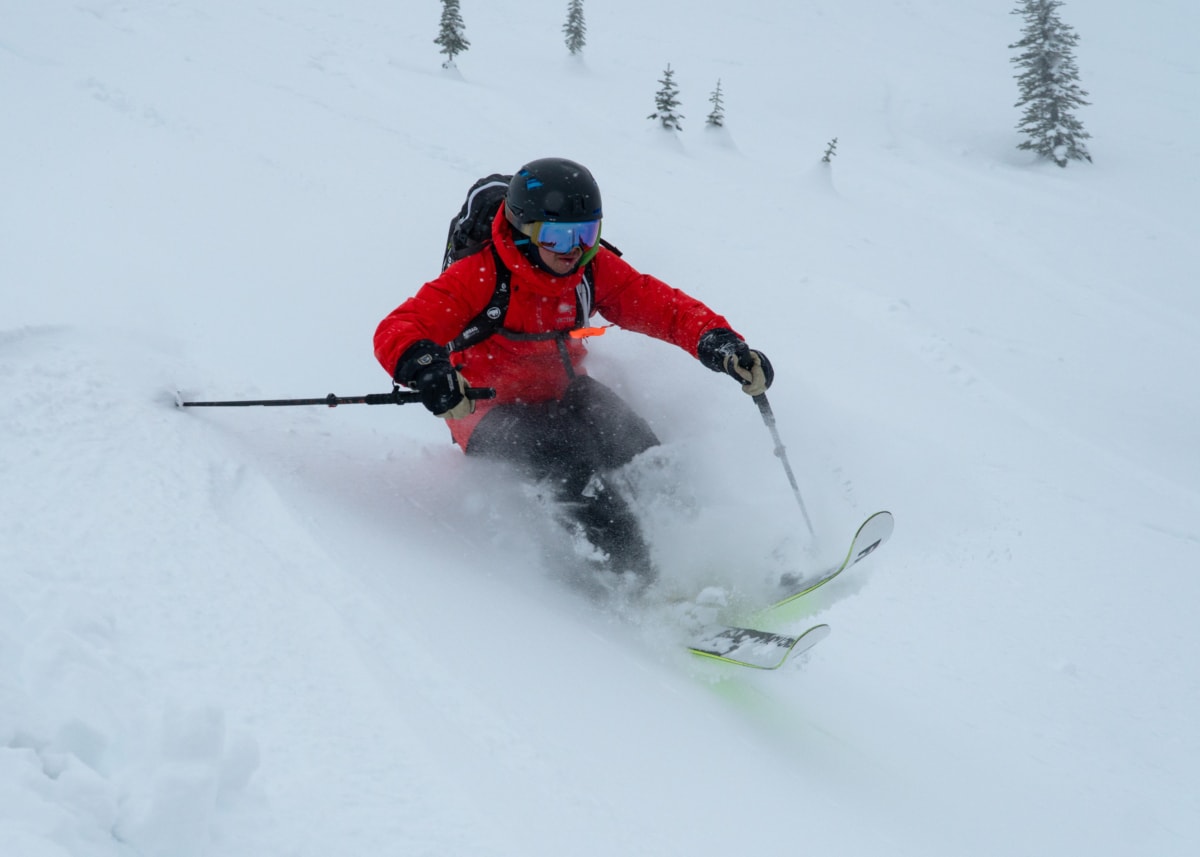 skier with red jacket thrown off balance by deep powder