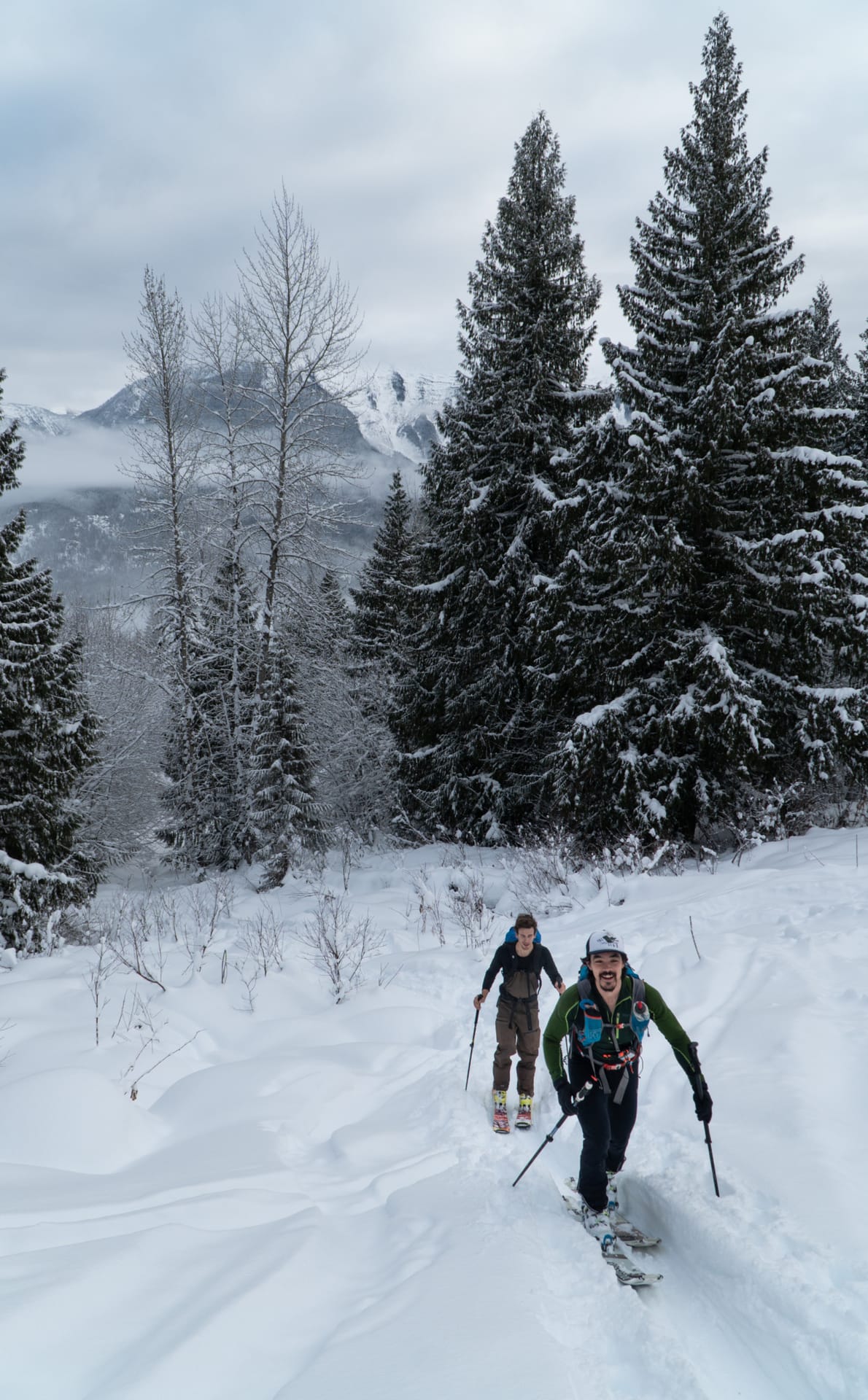 two men ski touring up the begbie shoulder below treeline
