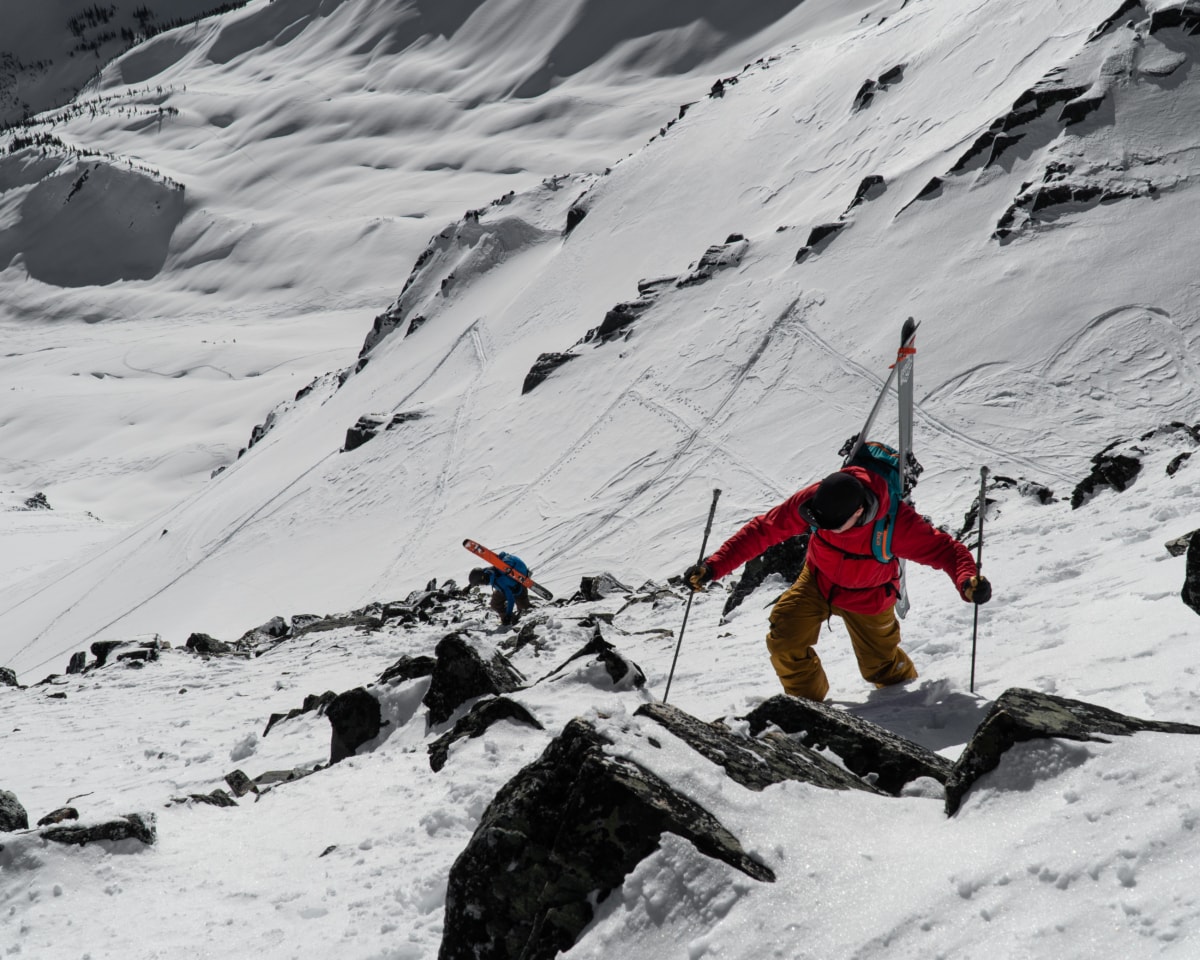 two skiers scrambling on a rocky ridge with exposure below