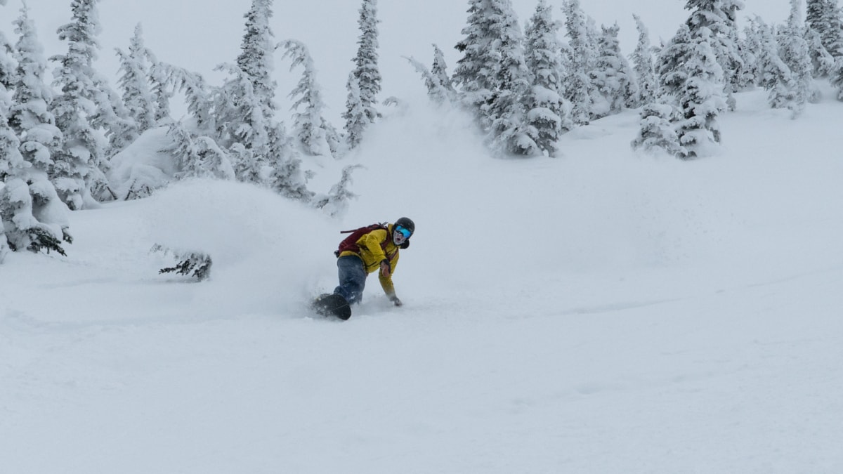 snowboarder carving through powder with hand on the surface