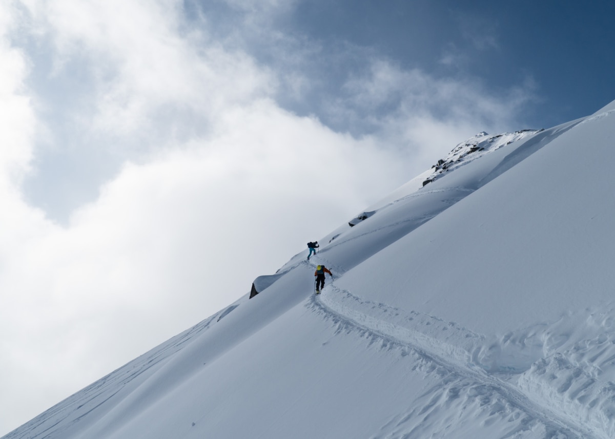 two ski tourers ascending the se face of video peak in the alpine