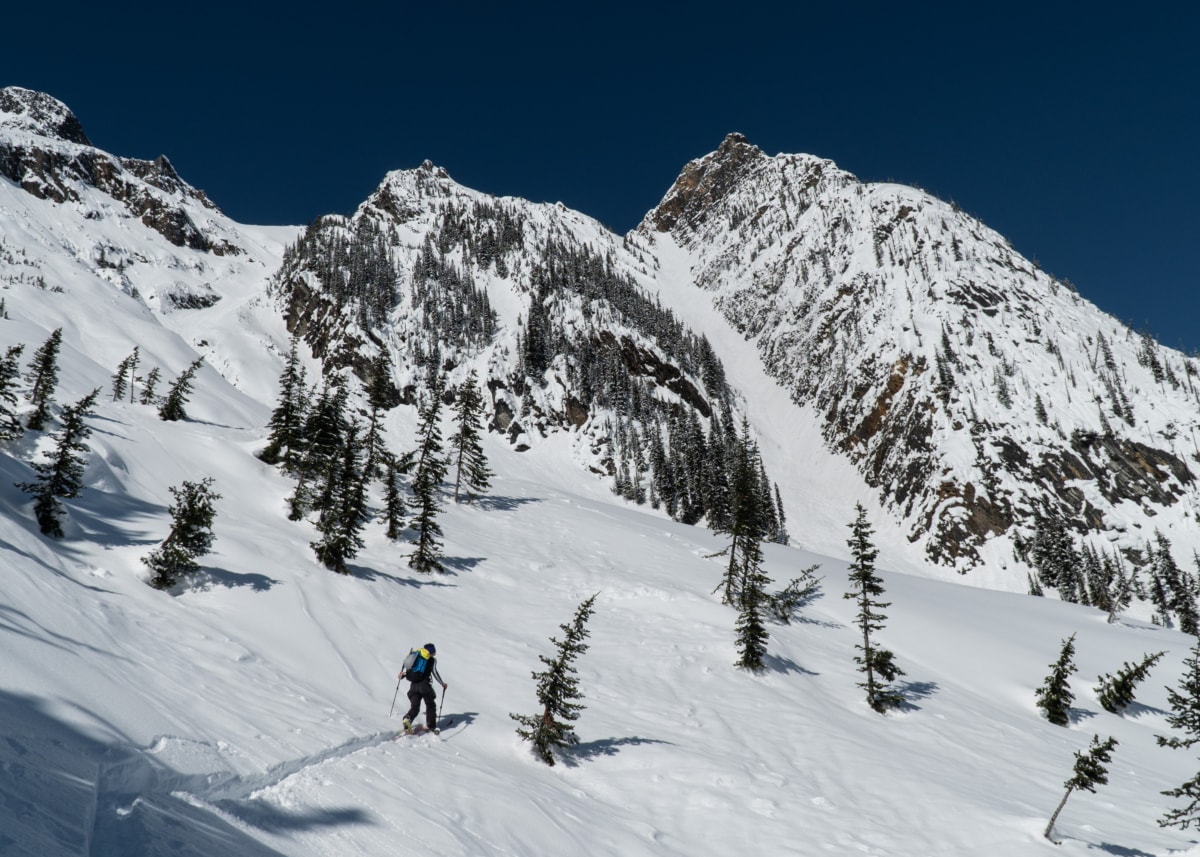 man ski touring up the se face of ross peak in winter