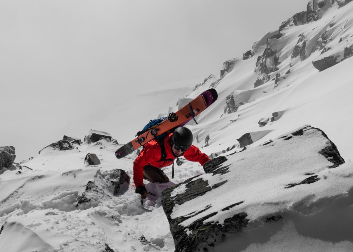 skier booting up a rocky ridge in mid winter