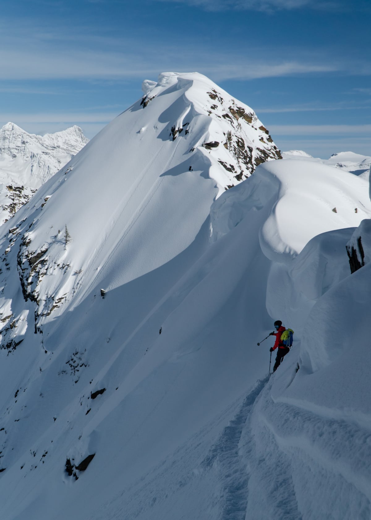 skier pointing at an alpine feature while standing under a cornice in courgar creek west 1