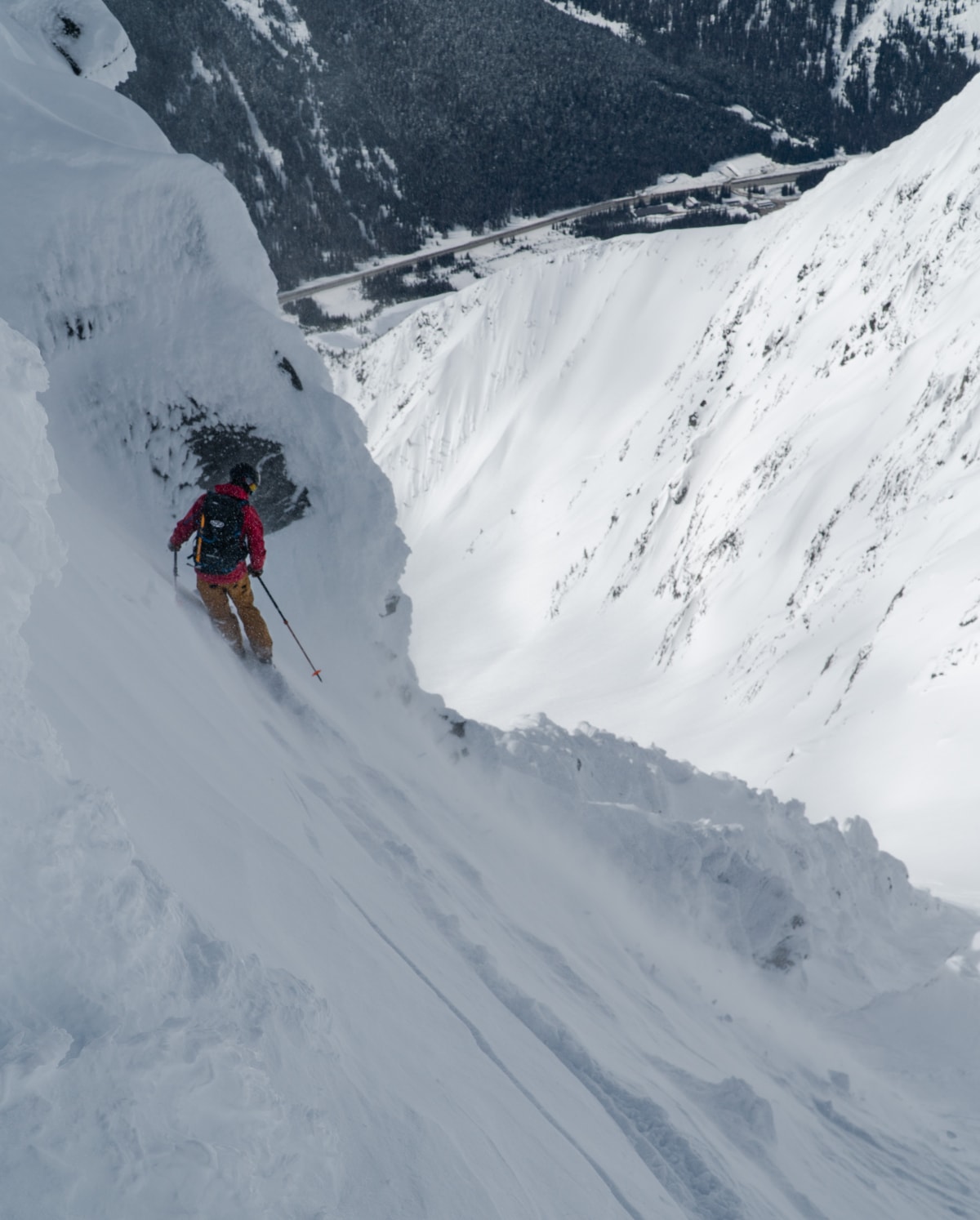 skier scoping out a very steep slope in rogers pass in winter