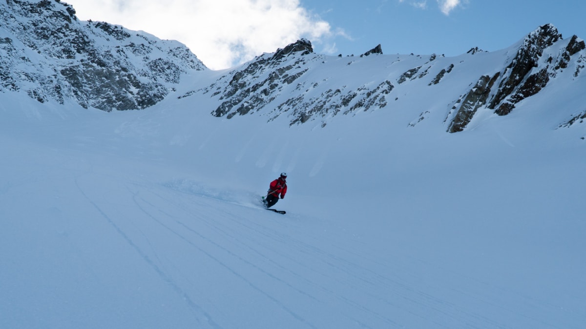 skier slashing a fast turn down an alpine bowl