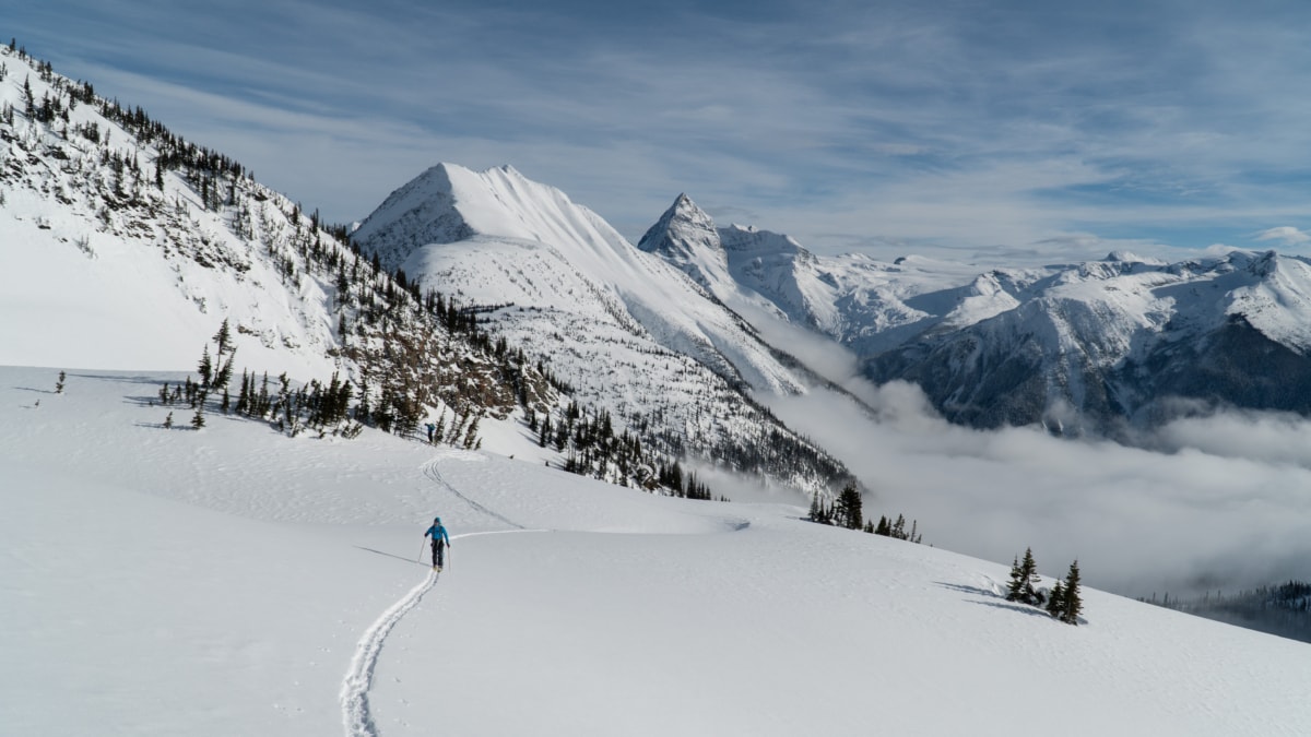 freddy walking up a snowfield with cheops mountain in the back
