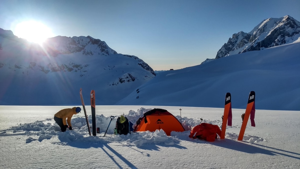 backcountry skier setting up camp on a glacier