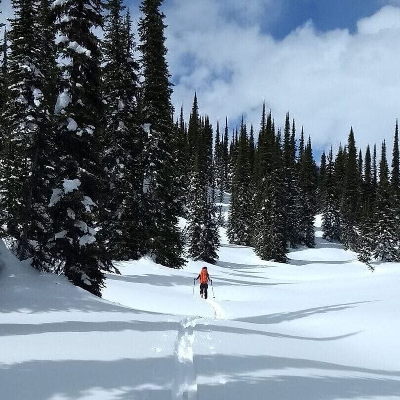 man skiing by farm pass in glacier national park
